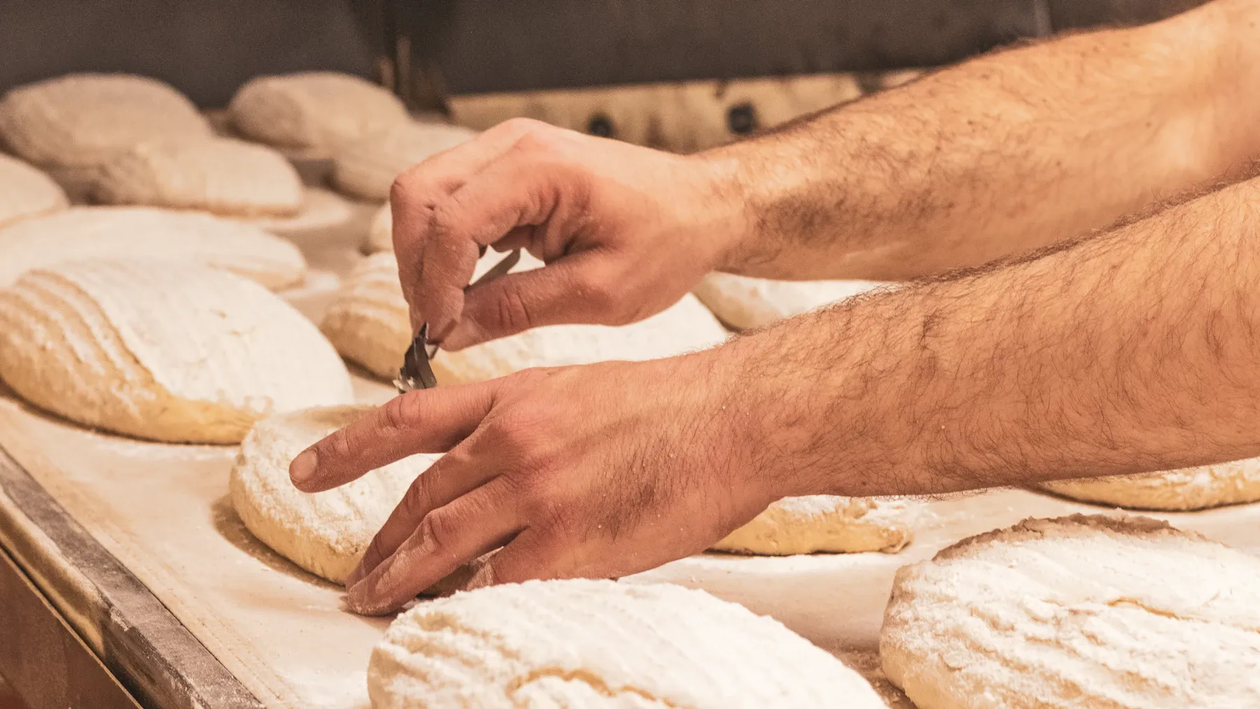 Hands preparing flour-dusted artisan bread.