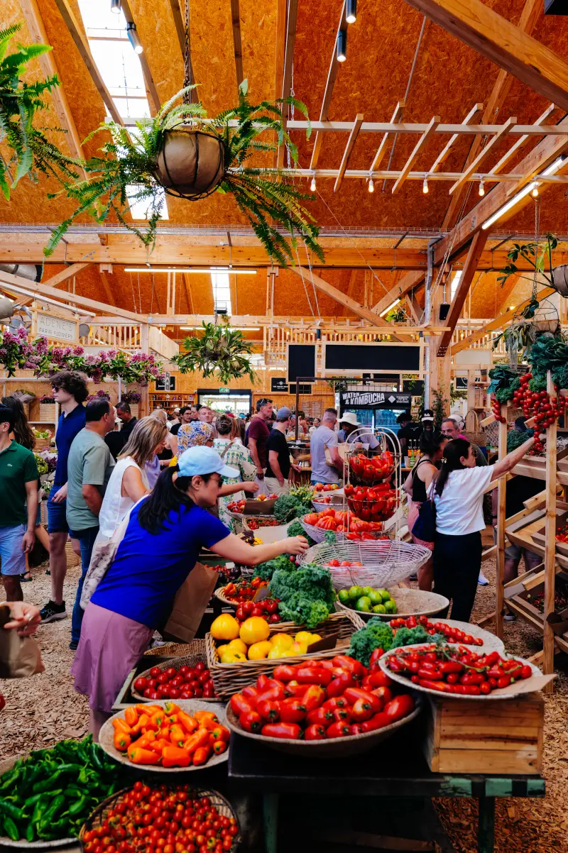 Shoppers choosing vegetables in a busy indoor produce market.